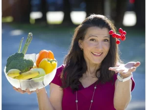 cristina sutter holding a bowl of vegetables and catching fruit mid air