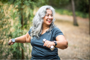 middle aged woman exercising outside with free weights