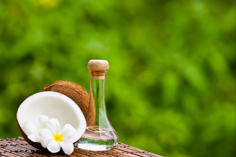 a bottle of oil sitting on a table next to a coconut