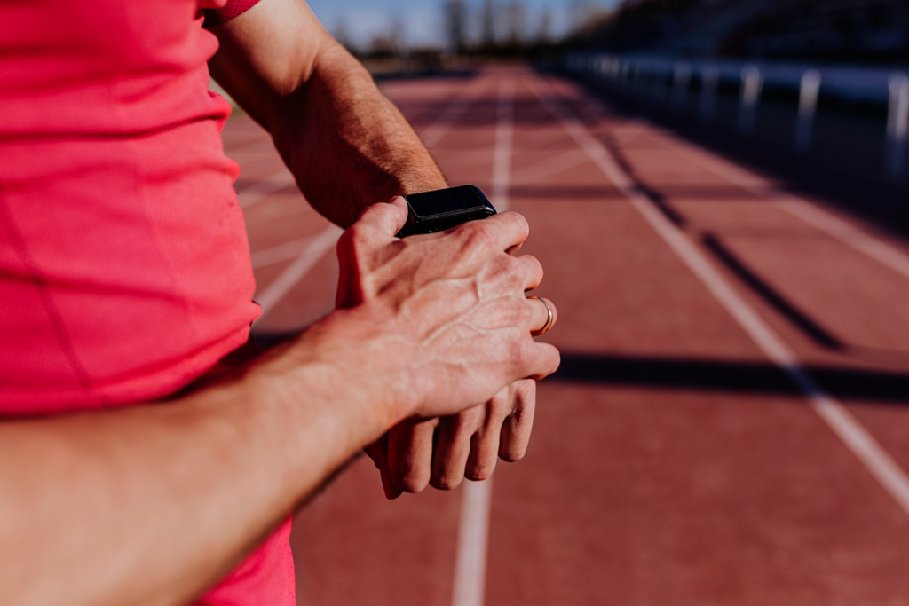Track athlete checking his smart watch, while standing at the track
